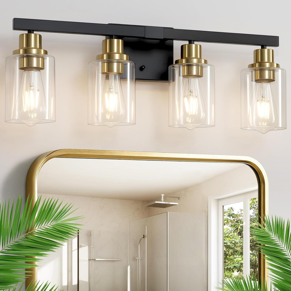 Four-light vanity fixture above a gold-framed mirror with clear cylindrical shades, black bar and gold sockets.