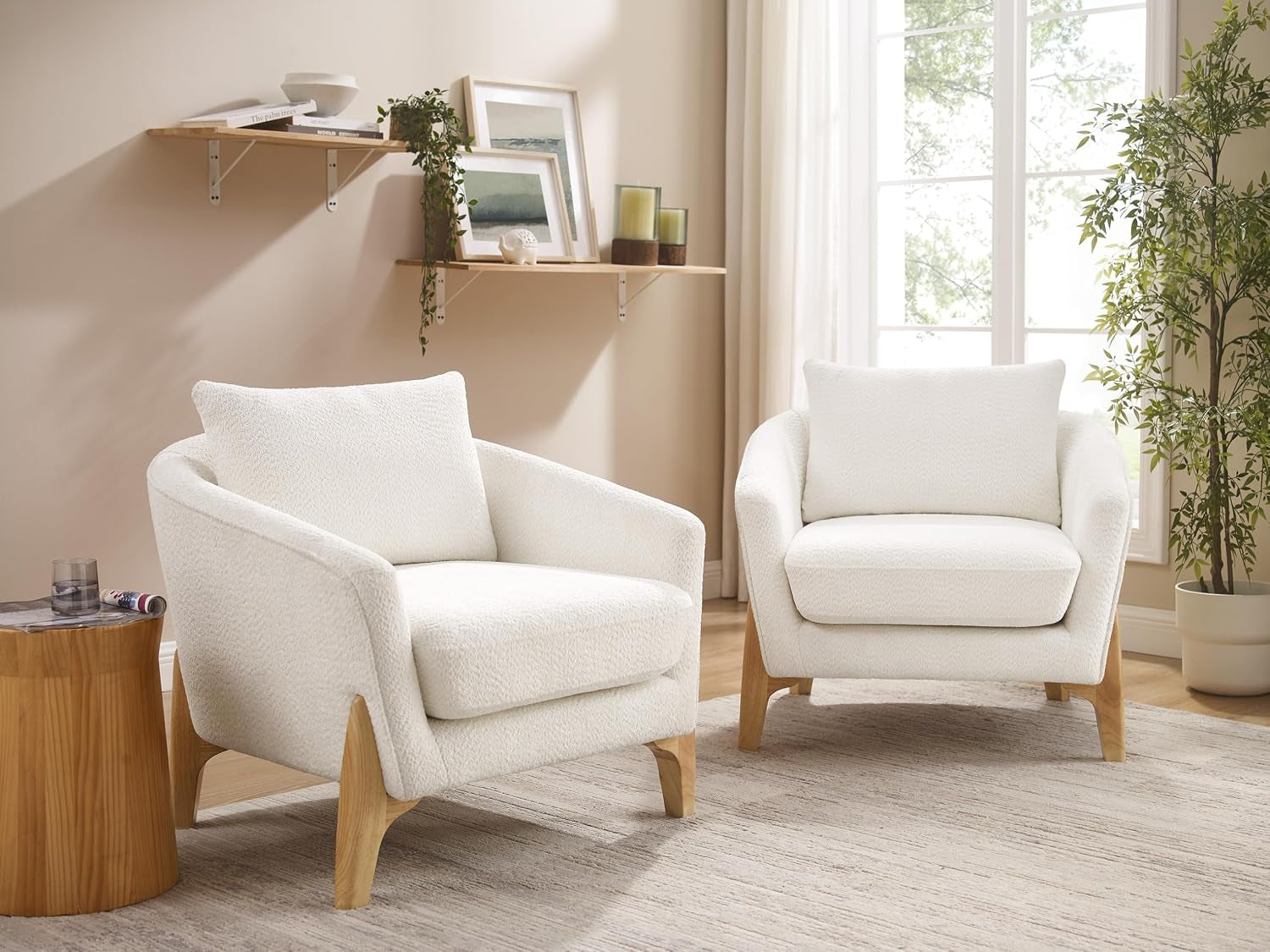 Pair of oversized white fleece accent chairs with light wood legs arranged in a sunlit living room.