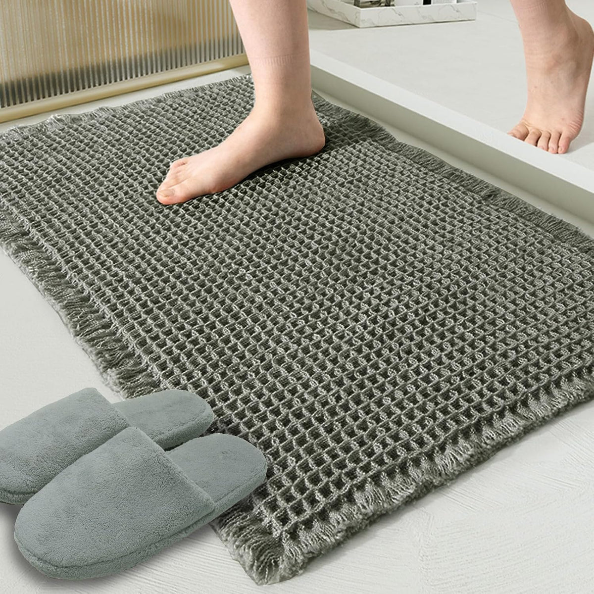 Close-up of a textured waffle bath mat by a shower step with a bare foot and slippers nearby