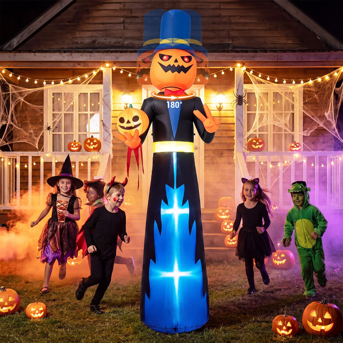 A tall pumpkin-headed gentleman inflatable stands among children in costume outside a decorated house.