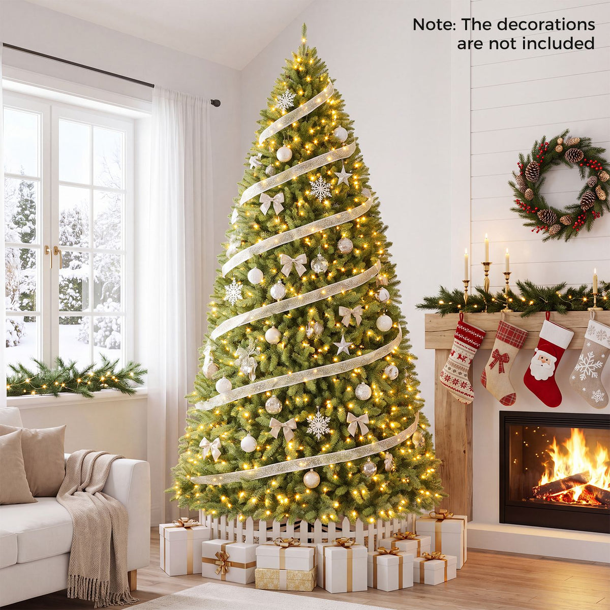A glowing Christmas tree wrapped in ribbon stands beside a fireplace and a light-colored sofa.
