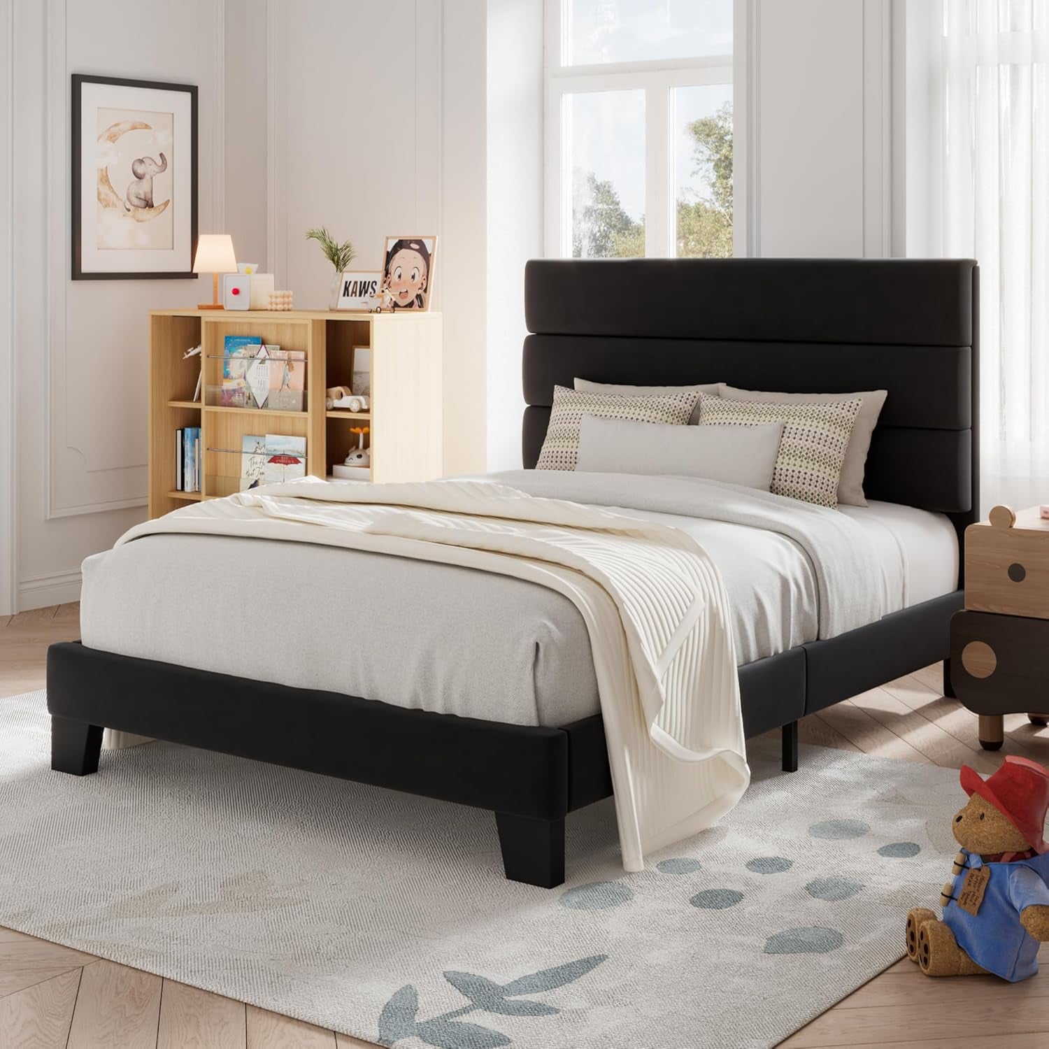 Three-quarter view of a black upholstered bed with a three-panel headboard in a child's bedroom.