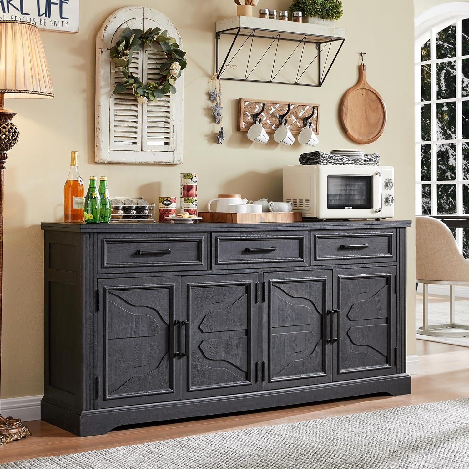 Front view of a charcoal-finished buffet with three drawers and decorative wall decor above it.