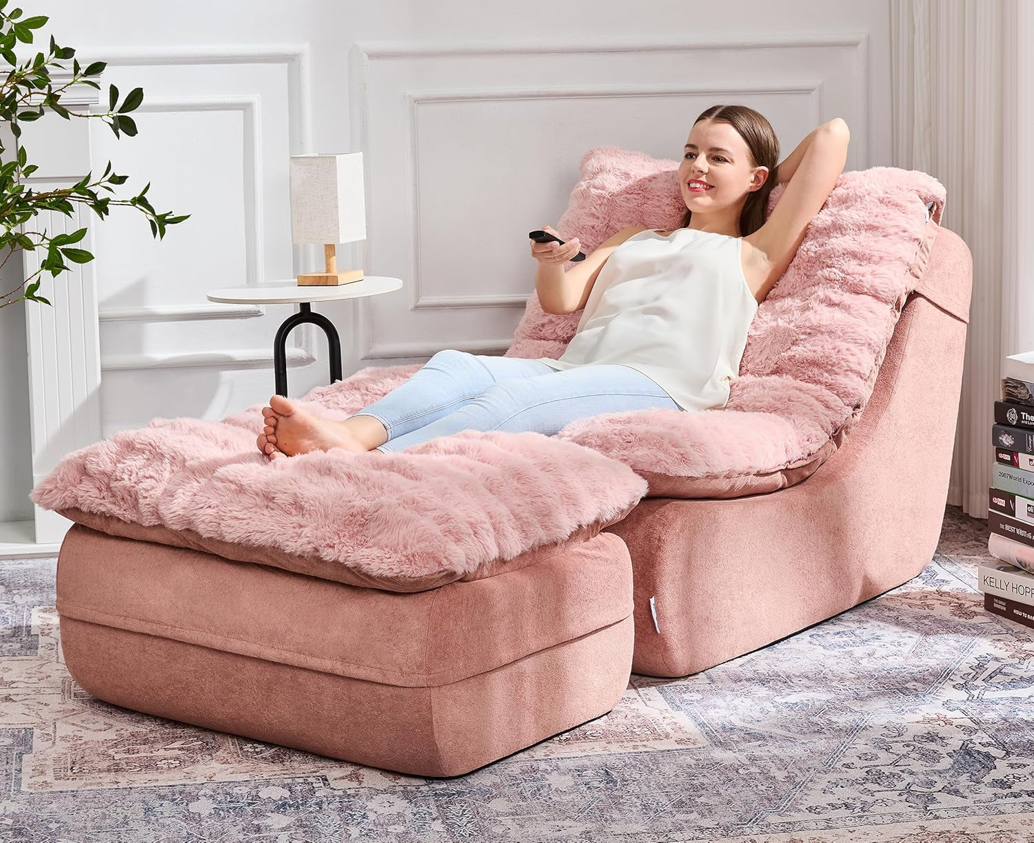 Woman reclining on a pink plush floor chair with a matching ottoman, holding a remote.