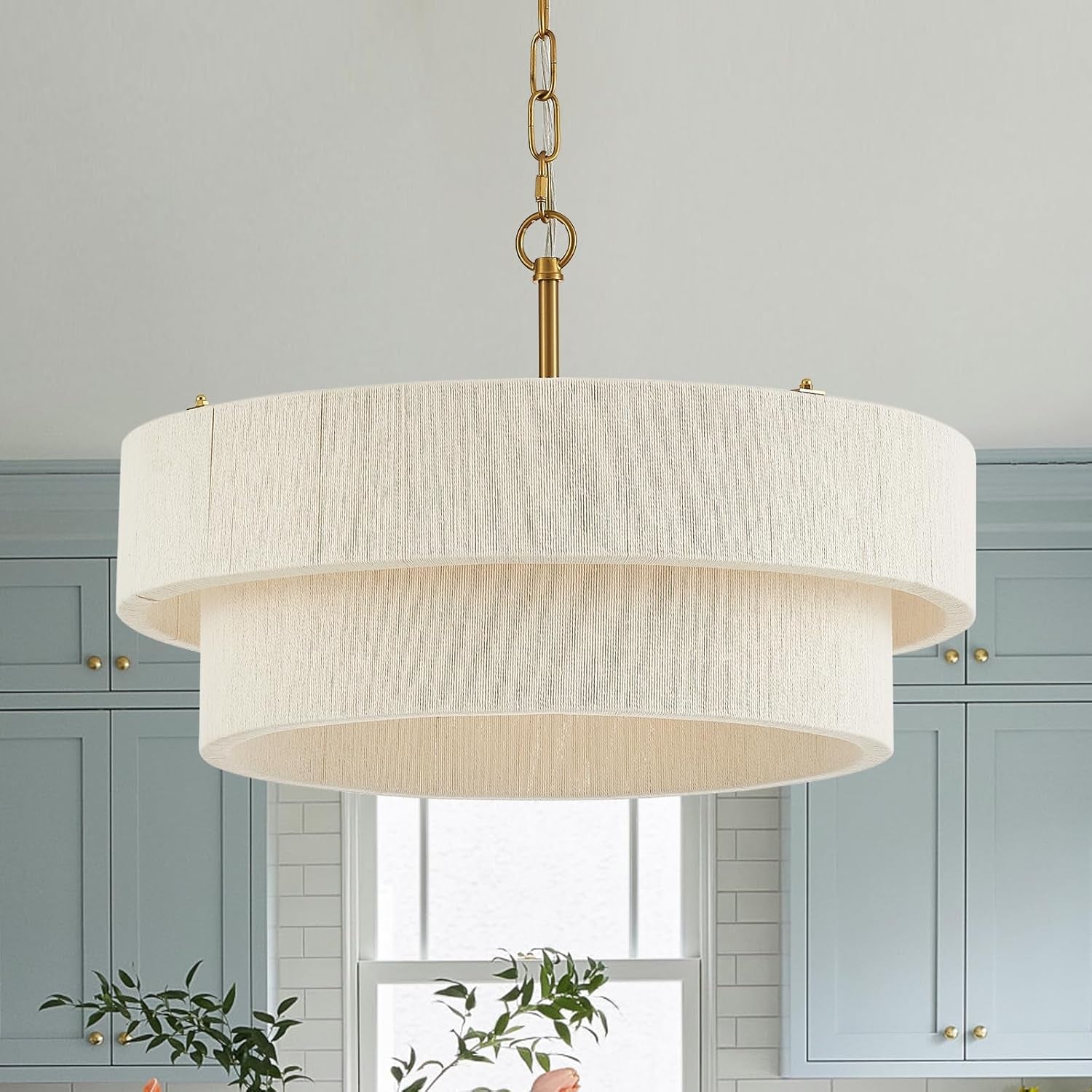 Cream hand-woven two-ring rattan chandelier close-up with brass chain above kitchen cabinetry