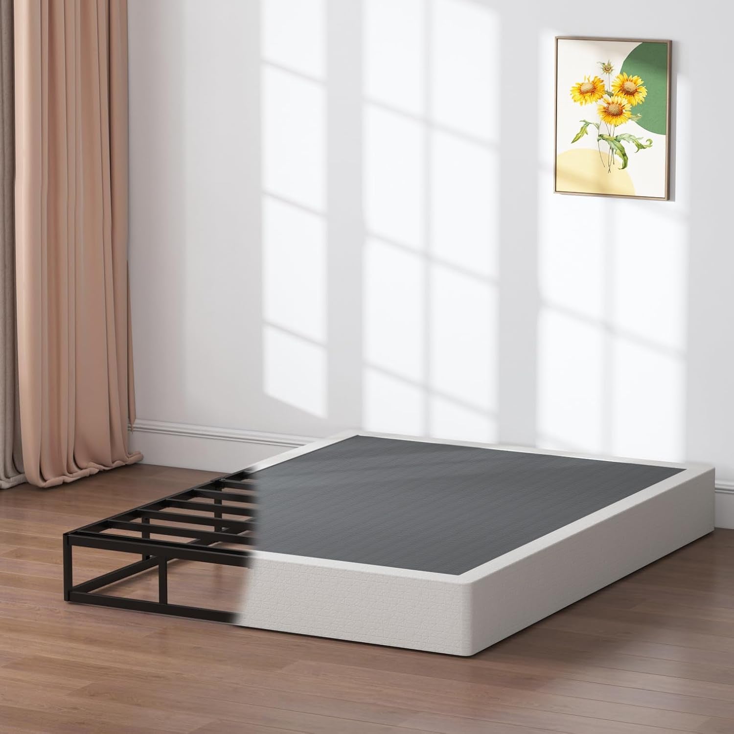Side corner of a sunlit room showing the black metal platform partially revealed next to a fabric box spring.