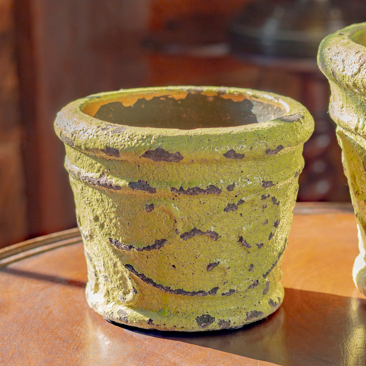 Close view of an empty green pot with a thick rim and mottled, distressed surface.