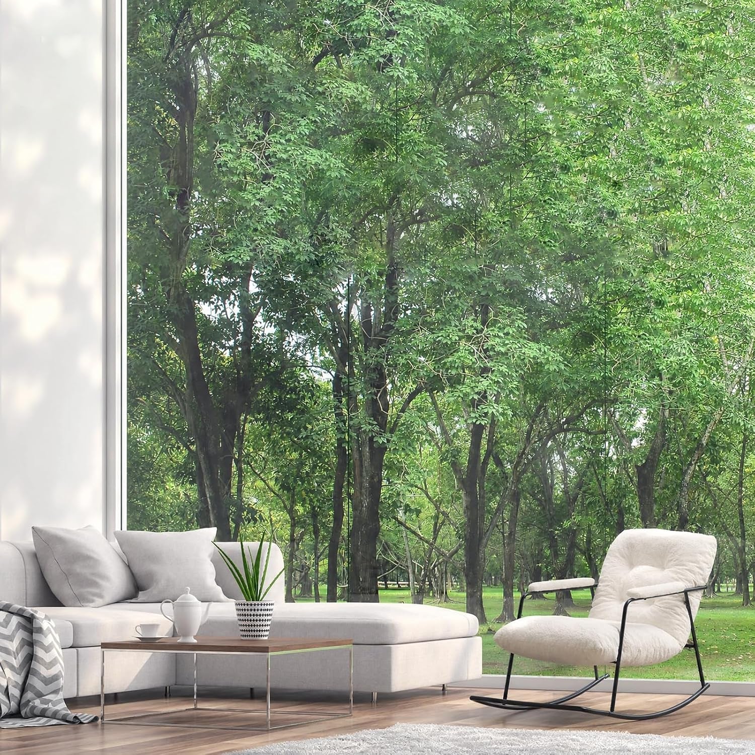 Living room with floor-to-ceiling window framing trees, light sectional and low coffee table left, cream bouclé rocking
