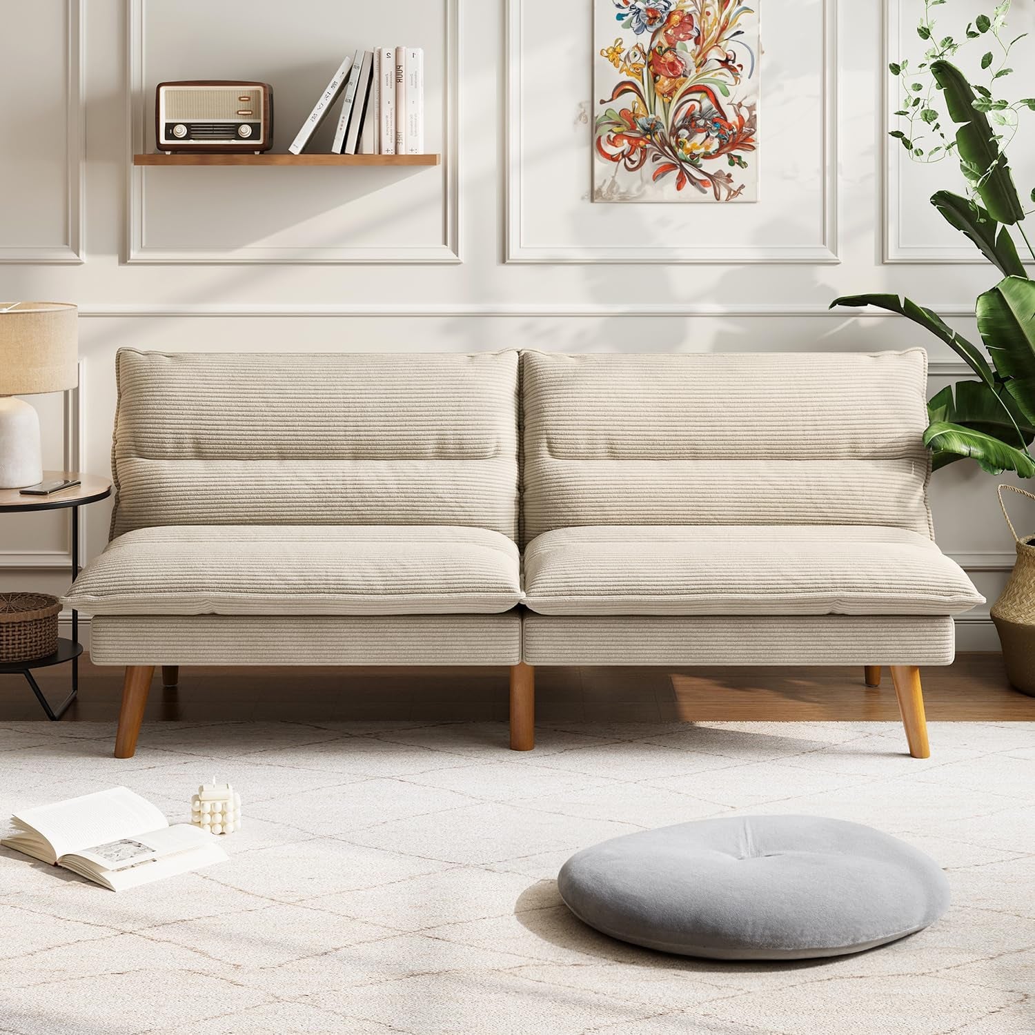 Front view of a beige corduroy futon sofa with two cushioned backrests and tapered wooden legs in a styled living room.