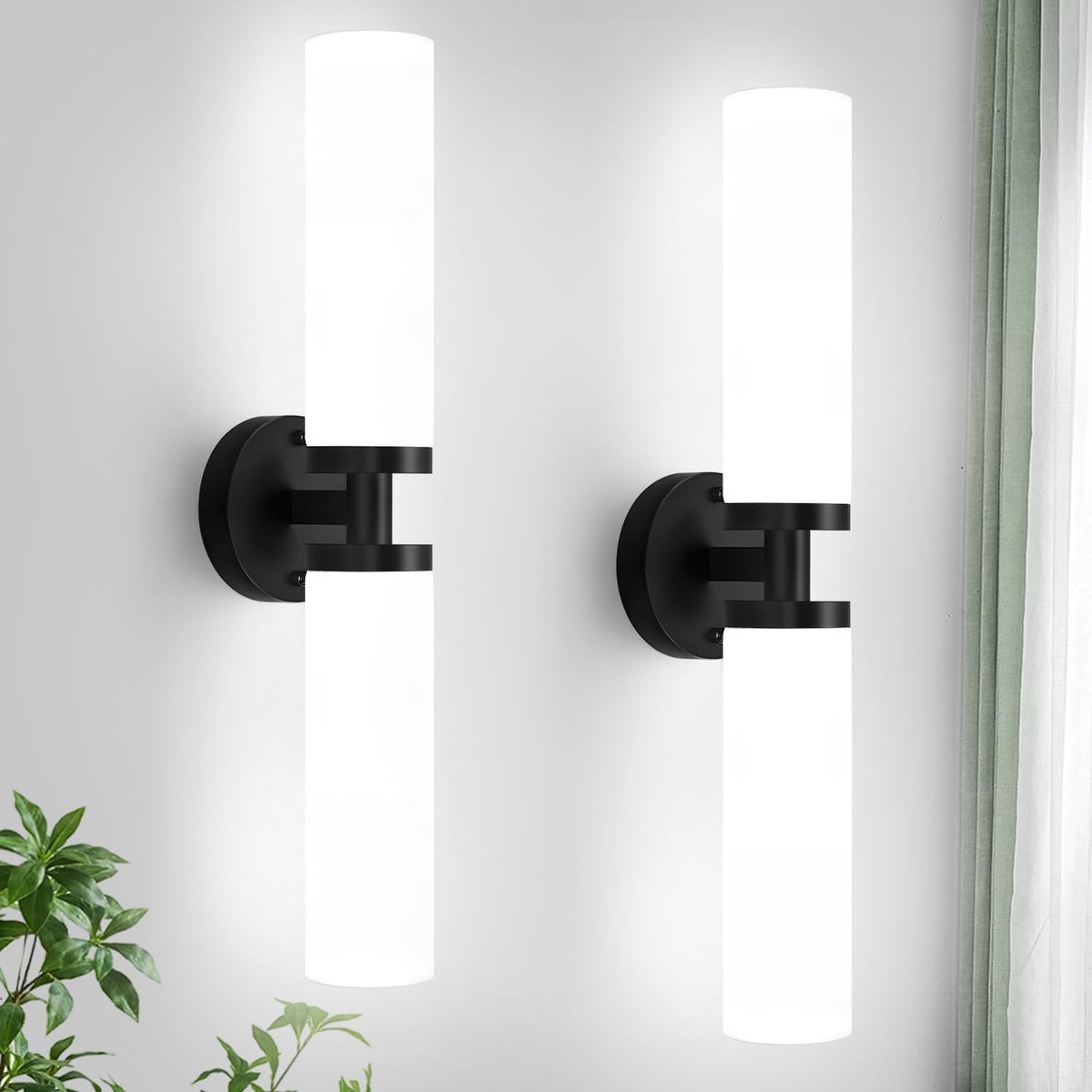 Two vertical matte black sconces with illuminated white cylindrical shades on a white wall.