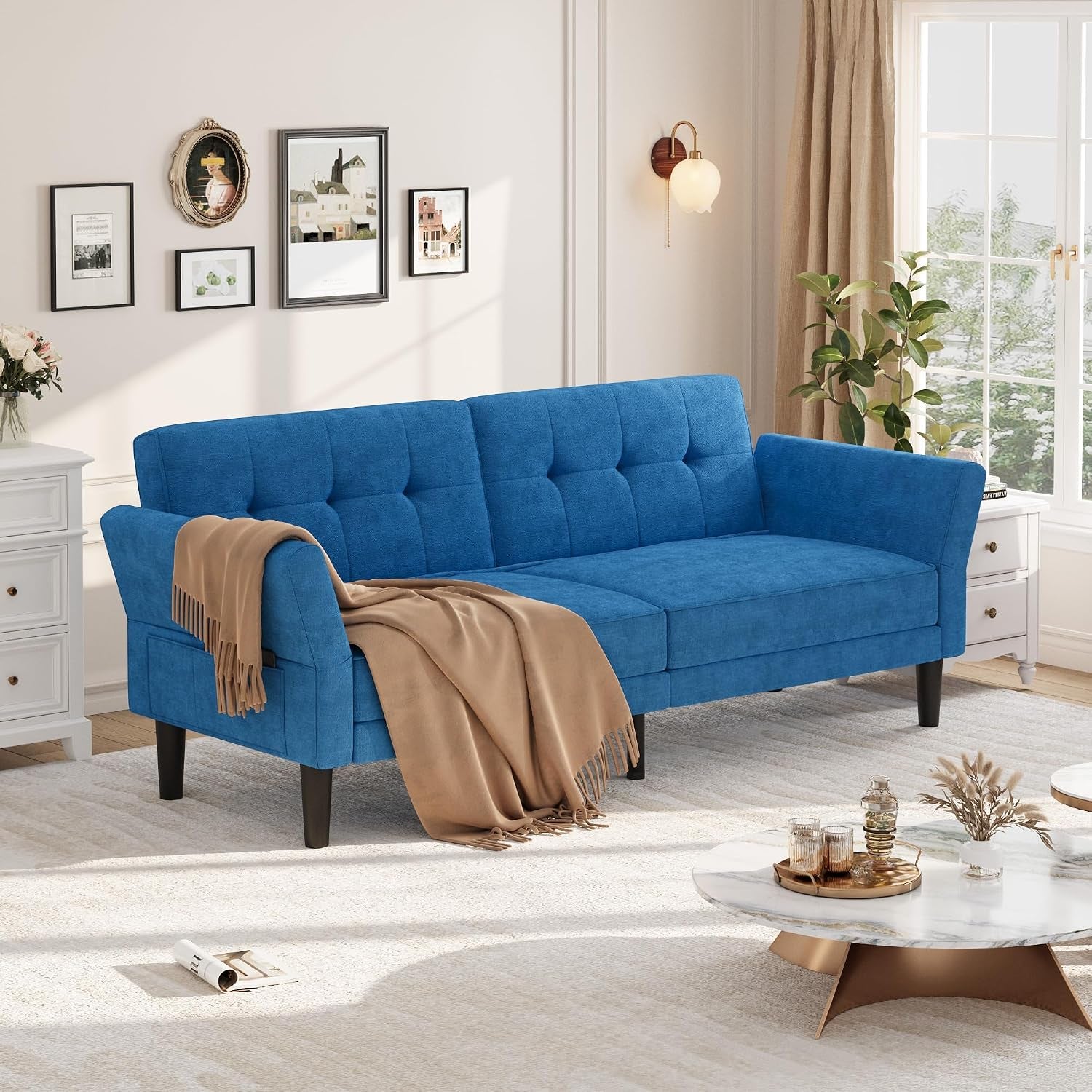 Blue chenille futon sofa angled front view with tufted back and black tapered legs in a living room