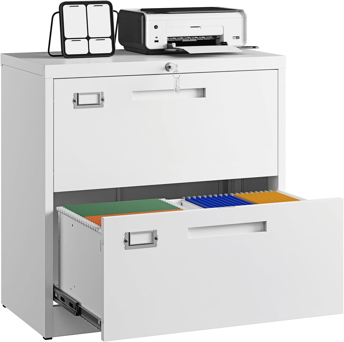 Cropped view of white filing cabinet top with keys in lock, printer and small calendar, and bottom drawer open with colored