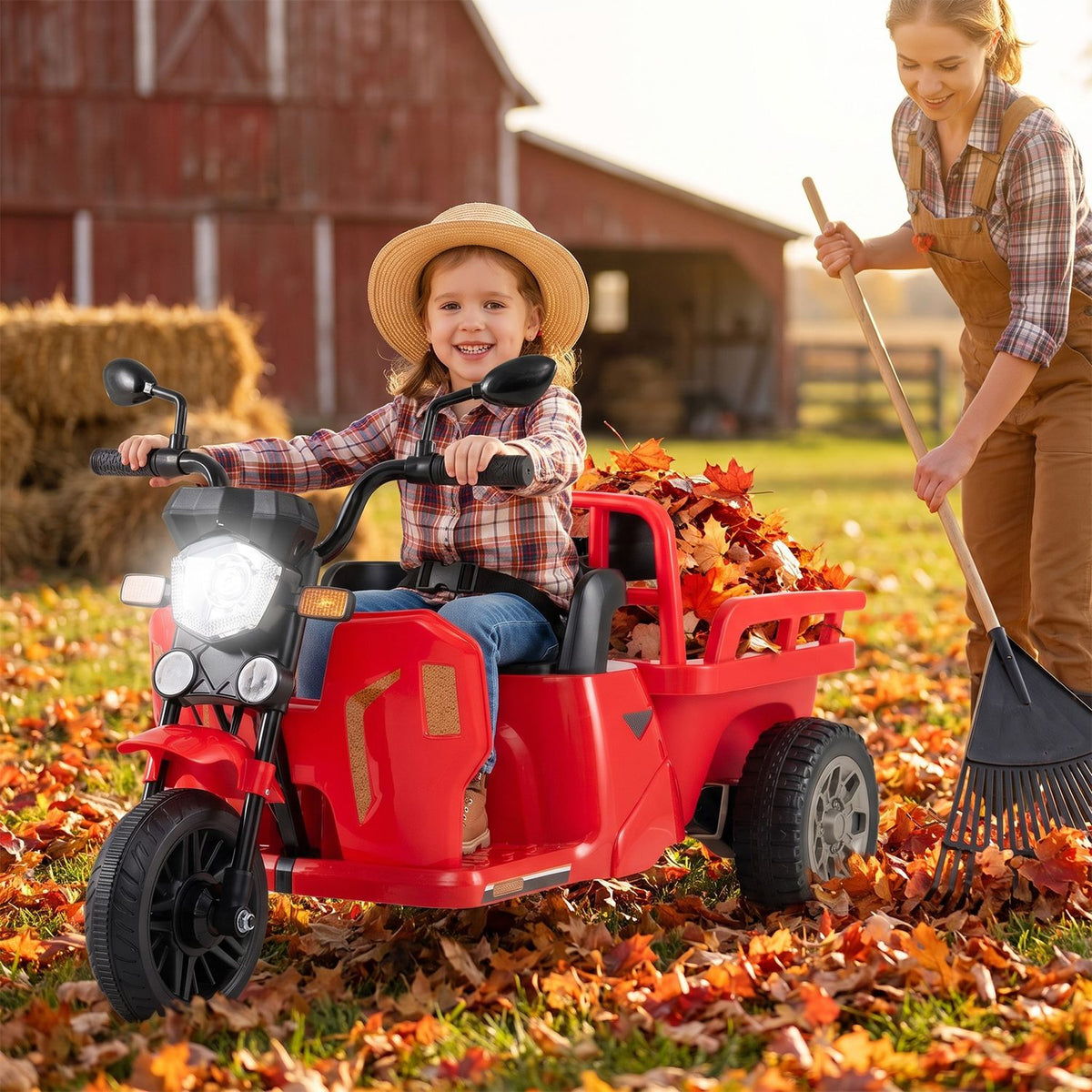 A child rides a red three-wheeled toy with a cargo trailer through autumn leaves as an adult rakes nearby.