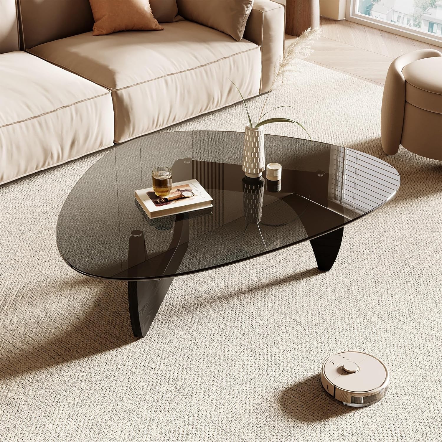 Smoked triangular glass coffee table with three curved dark wood legs on a light rug, staged with sofa and decor