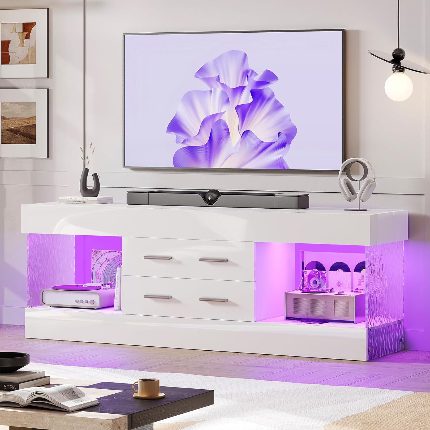 Glossy white TV stand with two open lit shelves and two center drawers under a wall TV