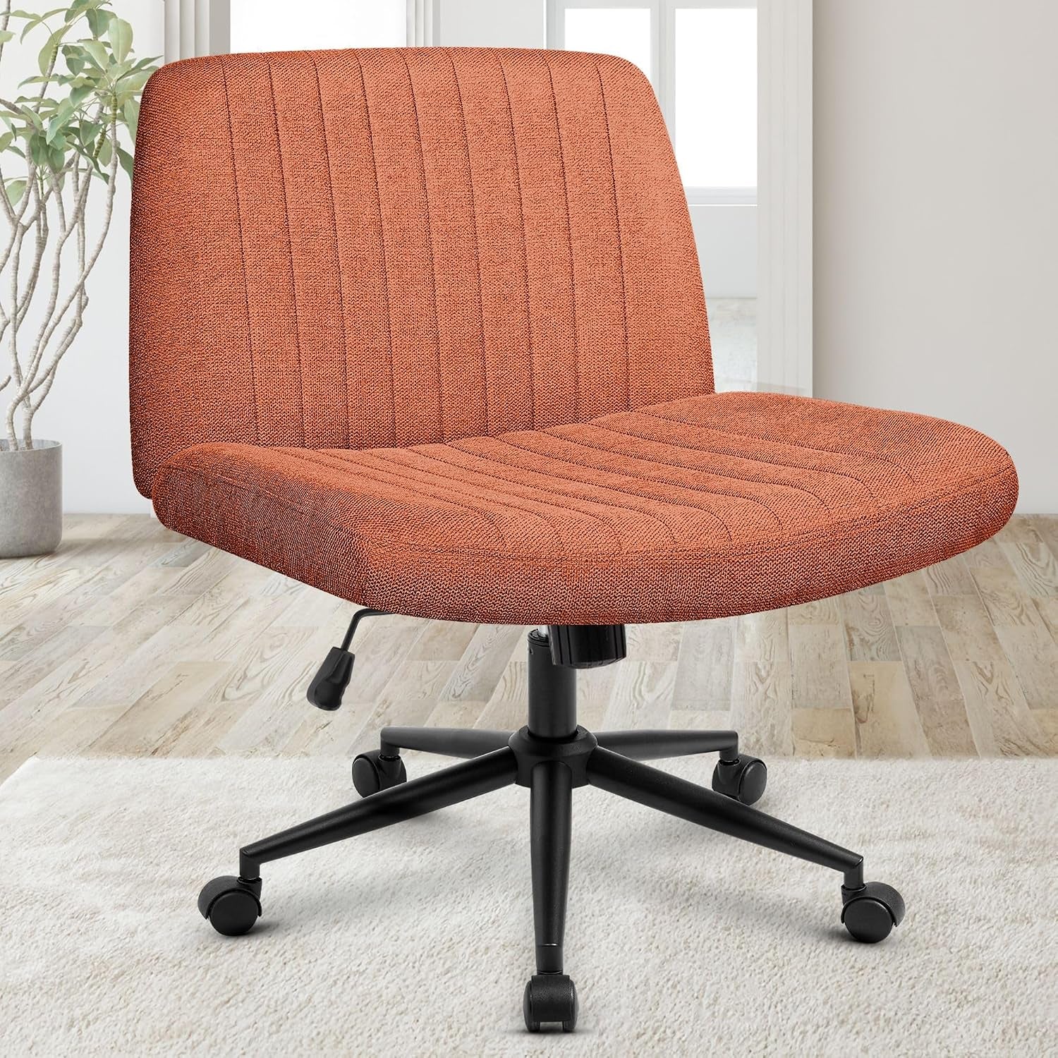 Orange fabric swivel chair showing padded seat and back, black base and caster wheels on a pale rug.