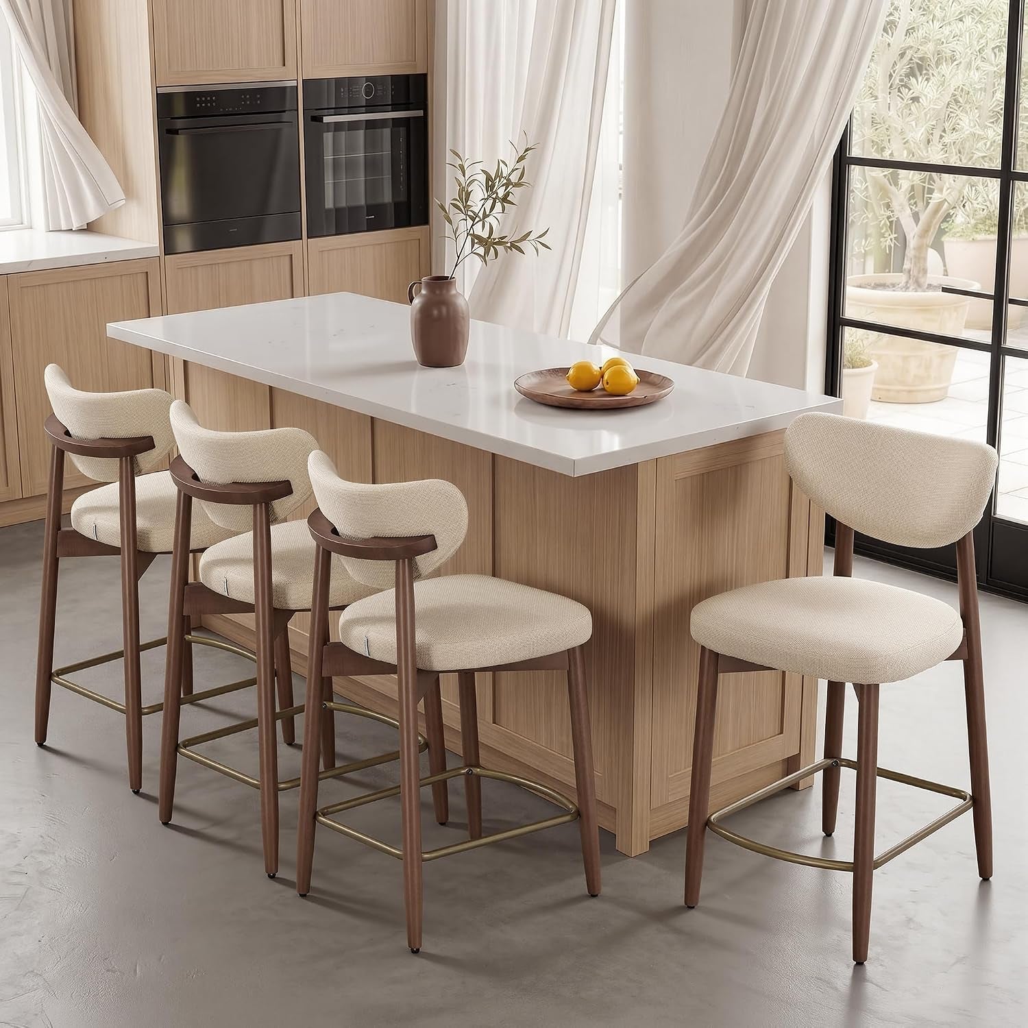 Four light beige fabric bar stools lined at a kitchen island with wood cabinets
