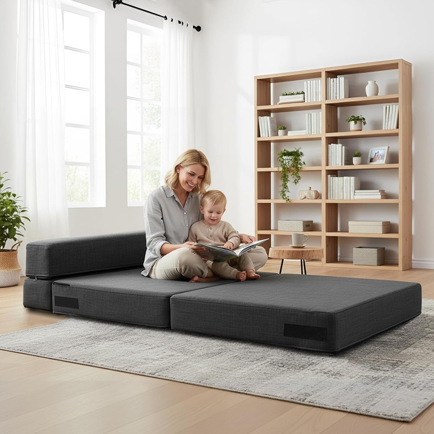Dark grey futon mattress laid flat on the floor with a parent and child sitting on it in a library-style room