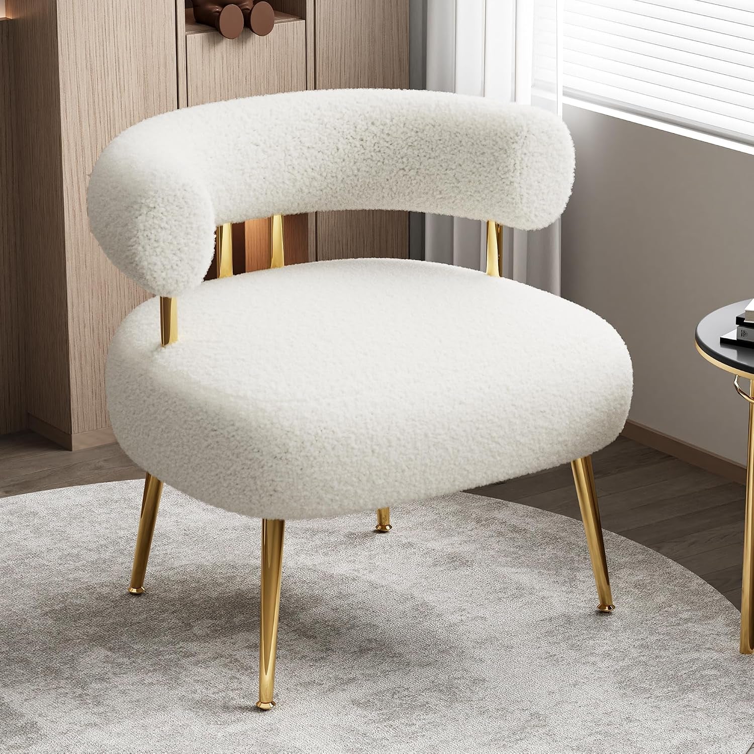 White sherpa rounded accent chair with gold legs on a light circular rug in a living space