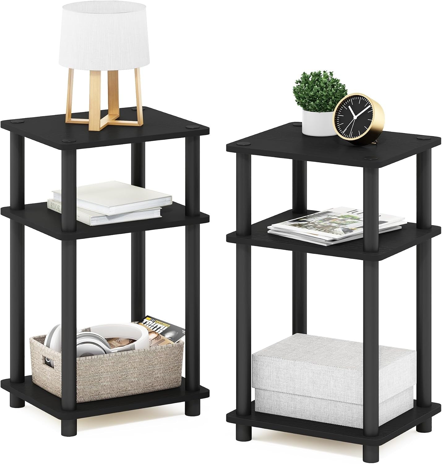 Two black three-tier end tables side-by-side with books, basket, lamp and clock on top