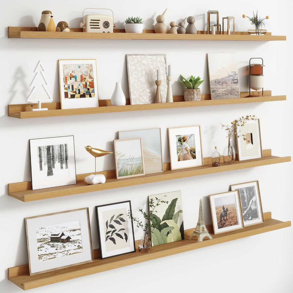 Four long natural wood floating ledges mounted on a white wall holding framed art and small decor