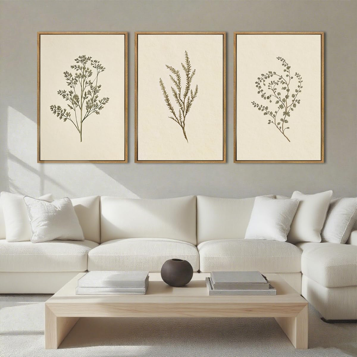 Living room with white sectional sofa and three framed botanical prints hung above it.