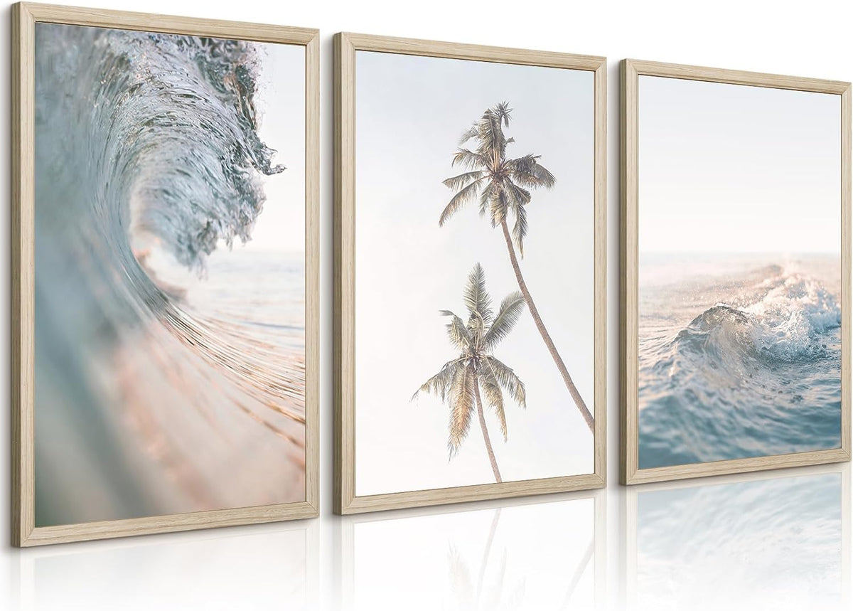Three wood-framed coastal prints side by side showing waves and palm trees, photographed at a slight angle.