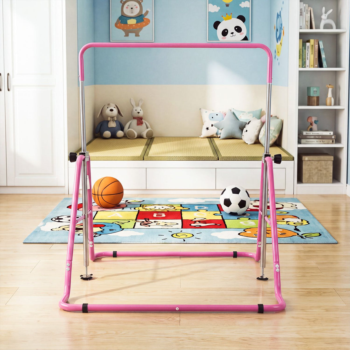 Pink gymnastics bar stands on a playroom rug, with a basketball and soccer ball behind it.