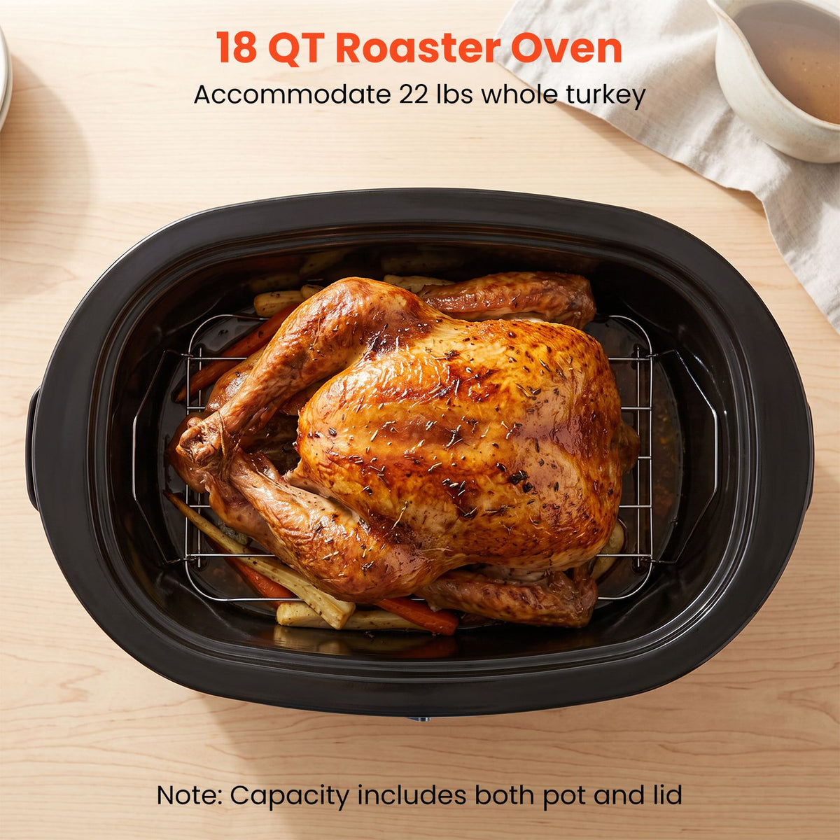 Roasted turkey sits on a rack inside a black oval roaster pan.