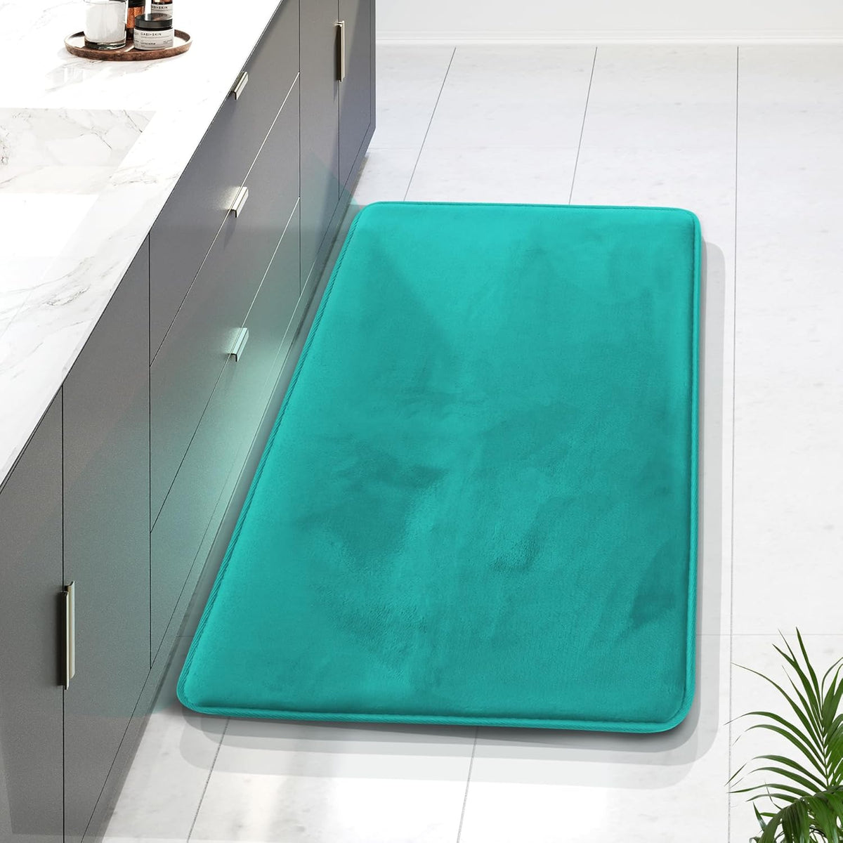 Overhead view of a teal rectangular memory-foam runner beside a dark gray cabinet on tiled floor.