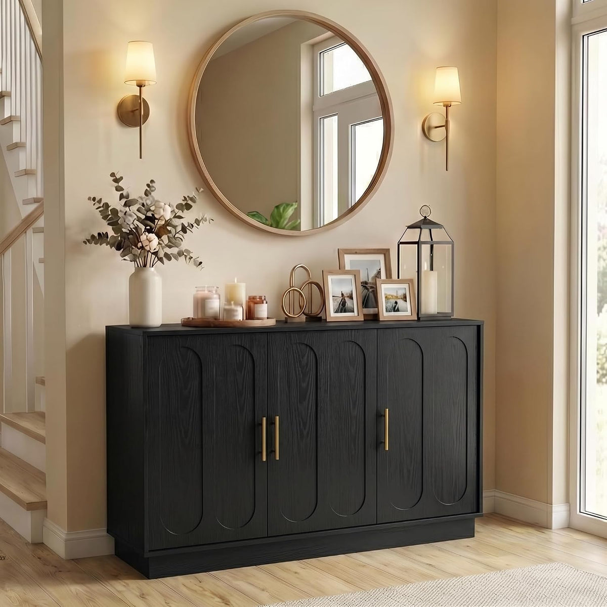 Matte black four‑door fluted cabinet with gold handles styled under a round mirror