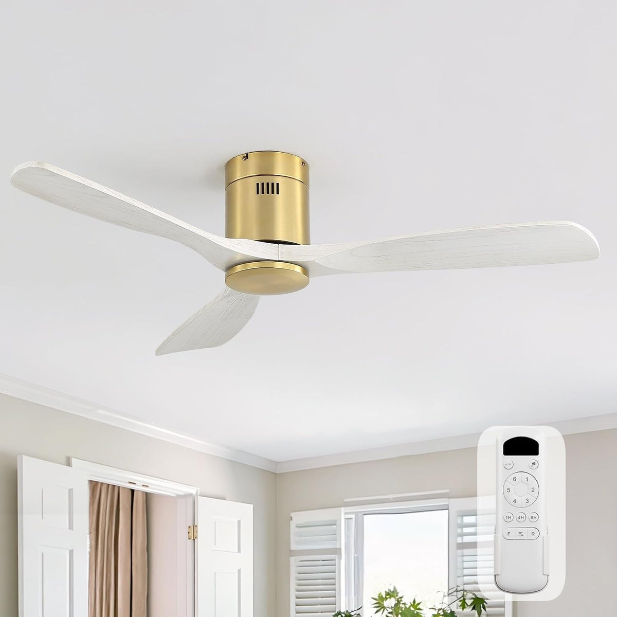 Flush‑mount fan with whitewashed blades and gold motor viewed from below in a sunlit bedroom