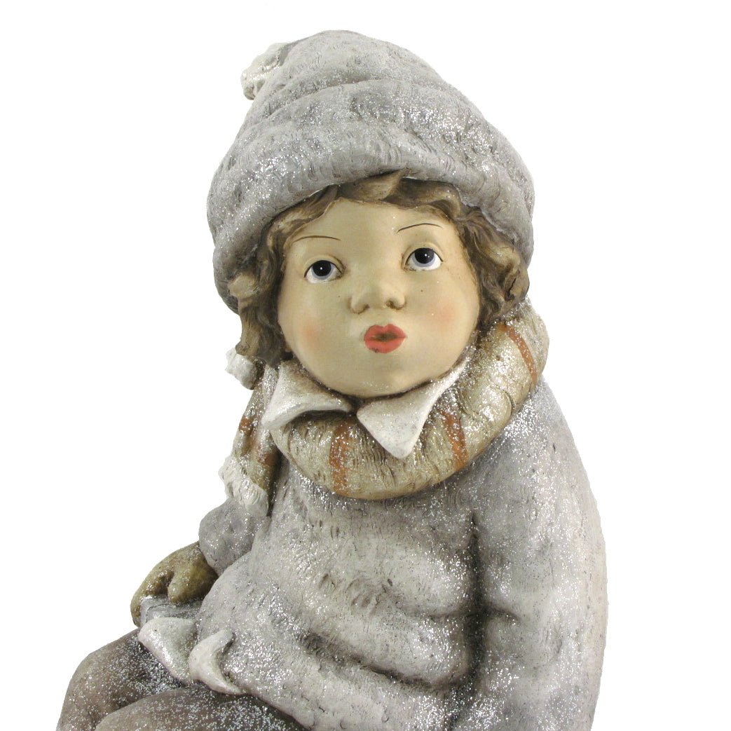 Close view of a seated winter figure in a glittery gray hat, scarf, and coat.