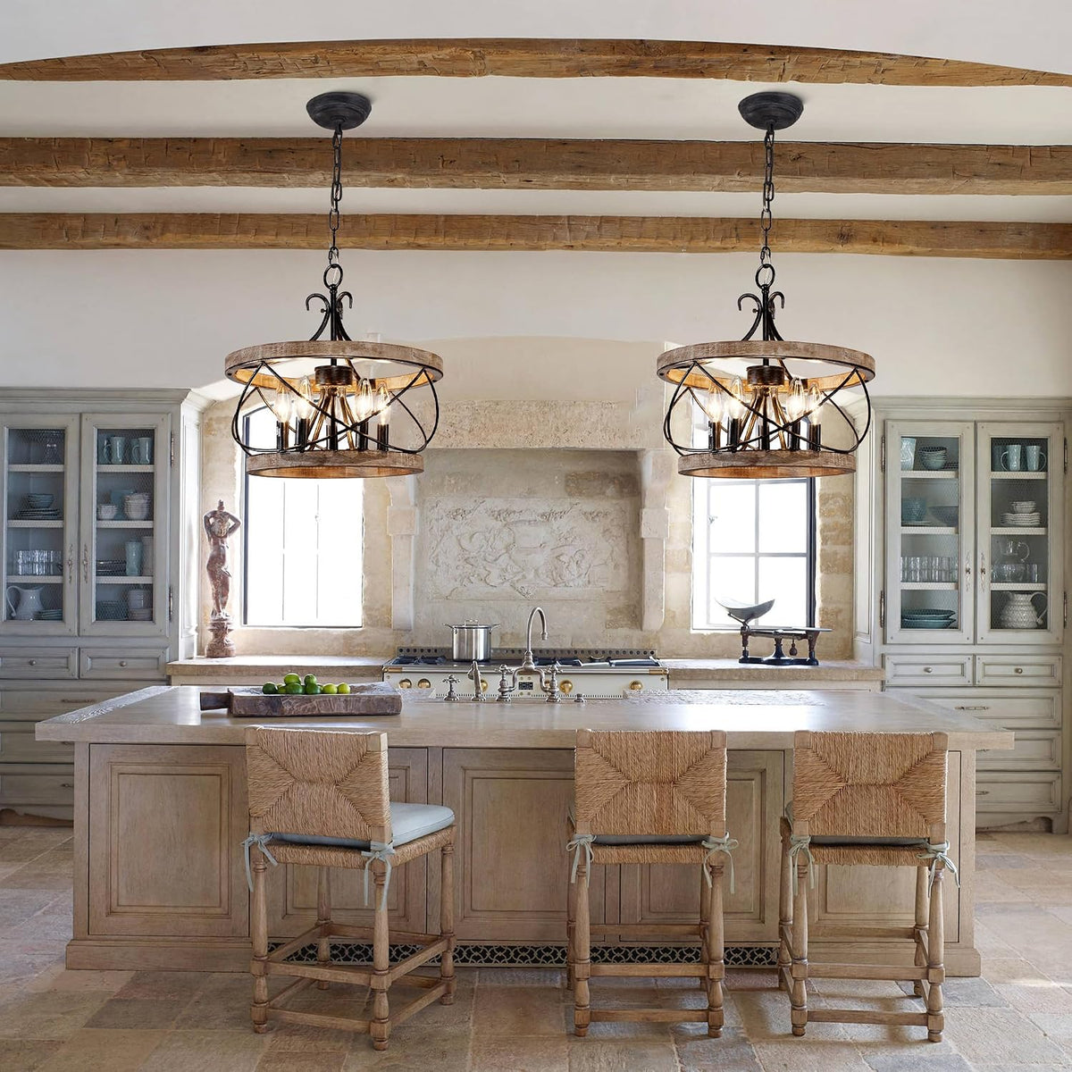 Two wood drum chandeliers with black iron accents suspended over a kitchen island in a wide kitchen setting