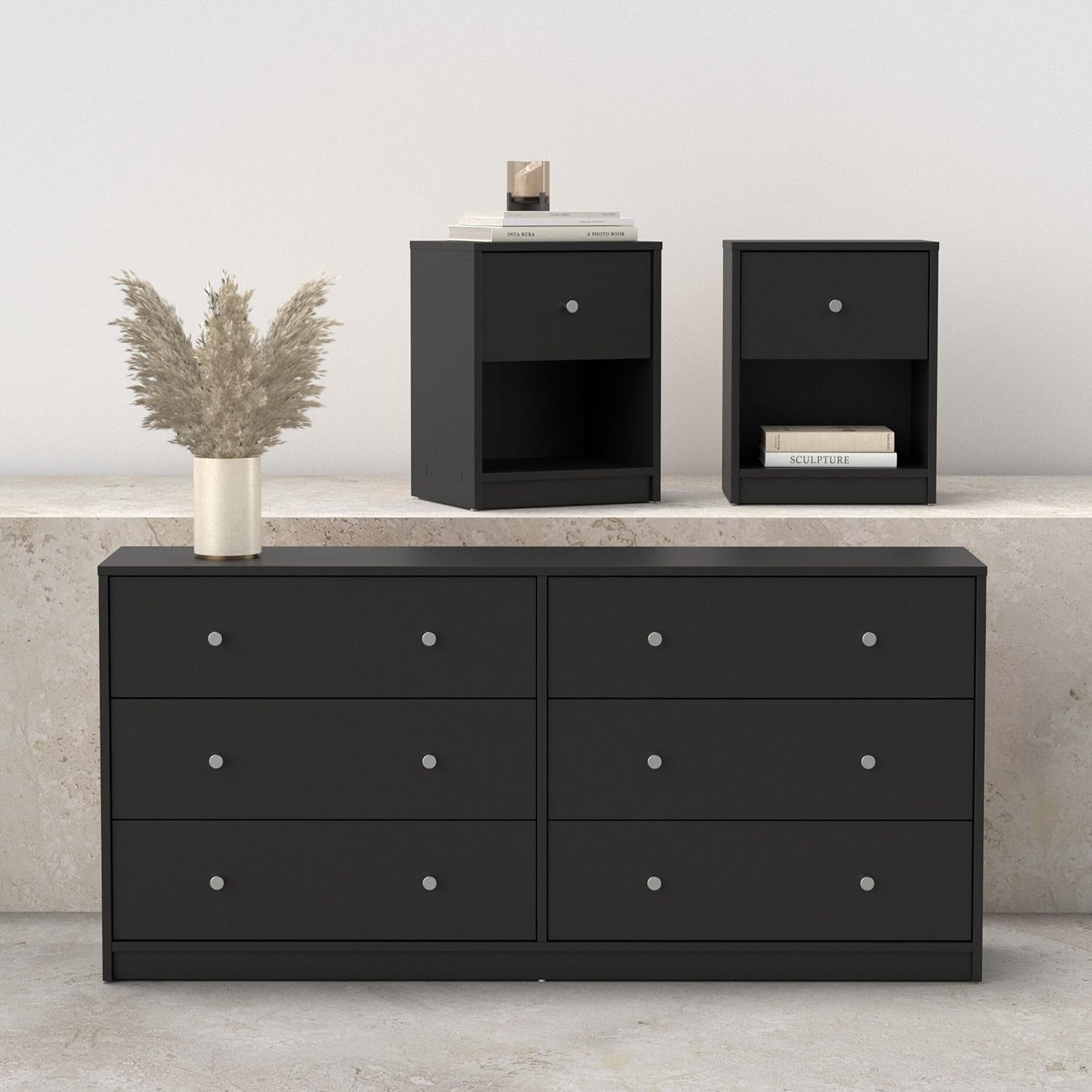 Front view of a black six-drawer dresser with two matching nightstands displayed on a stone ledge