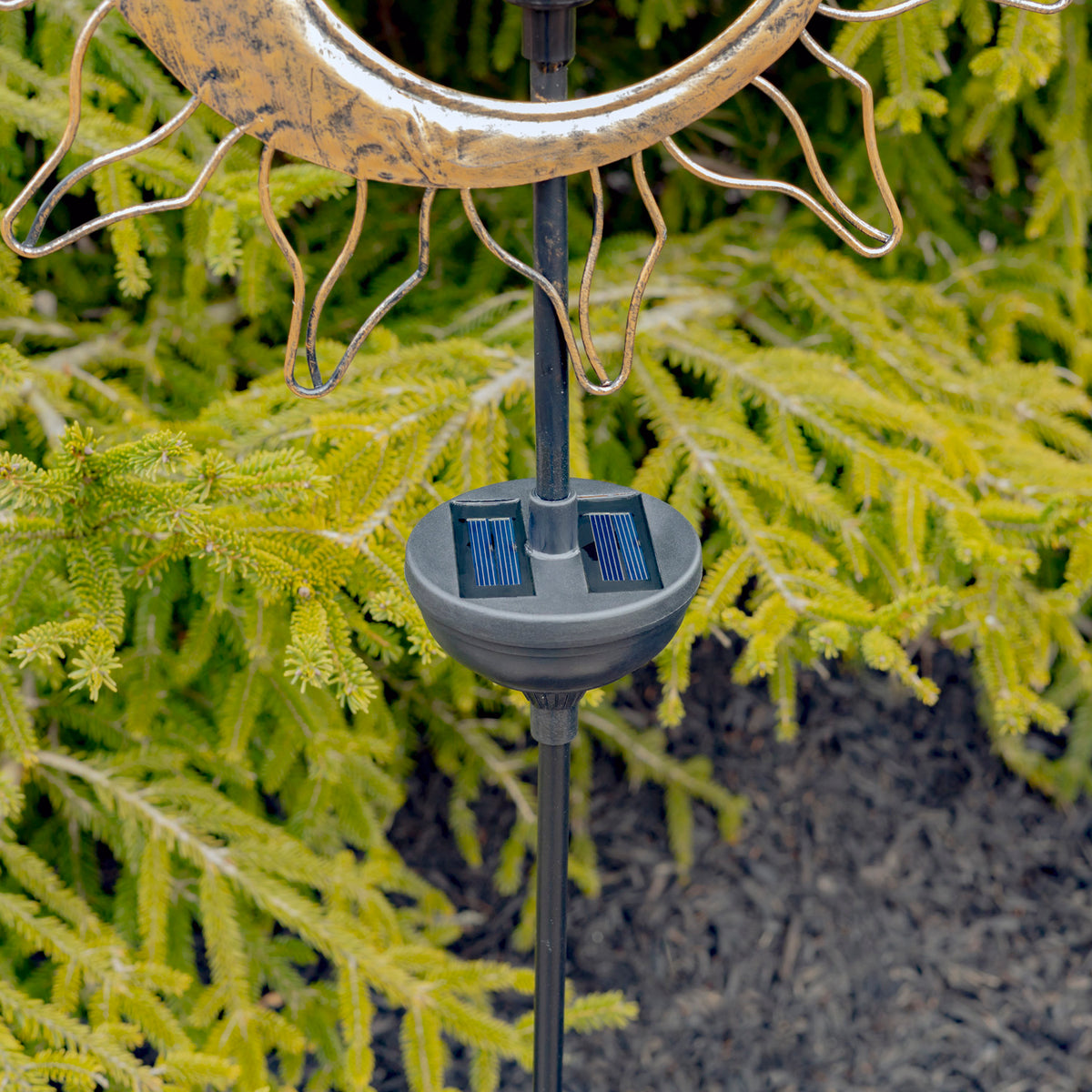 Close-up of the stake’s round solar panel housing beneath the lower edge of a gold sun-and-moon ornament.