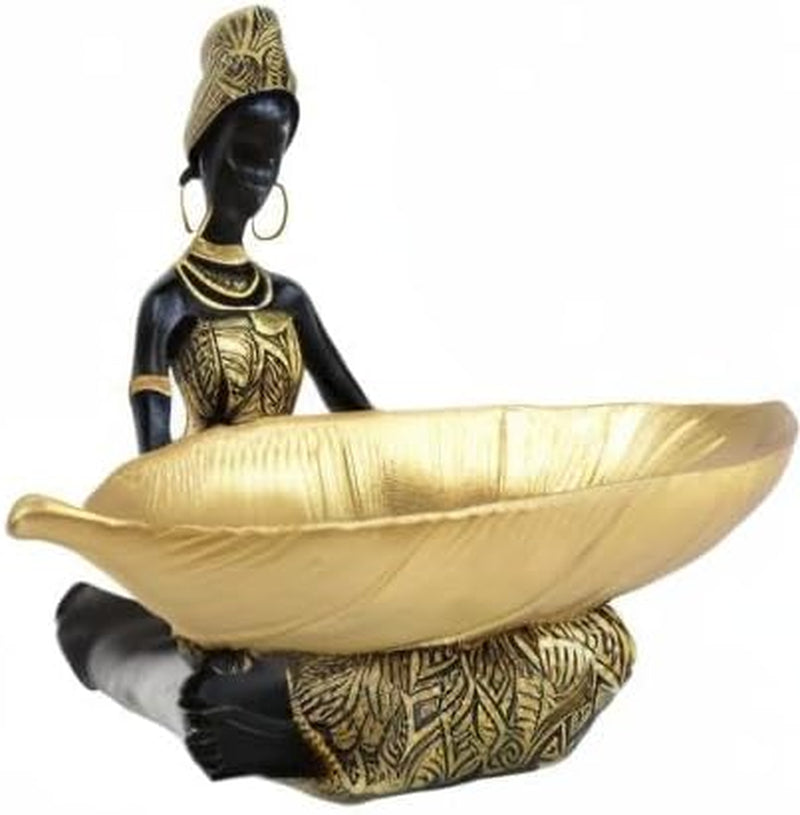 Side view of a kneeling figurine holding a wide textured leaf-shaped tray, black figure with gold accents