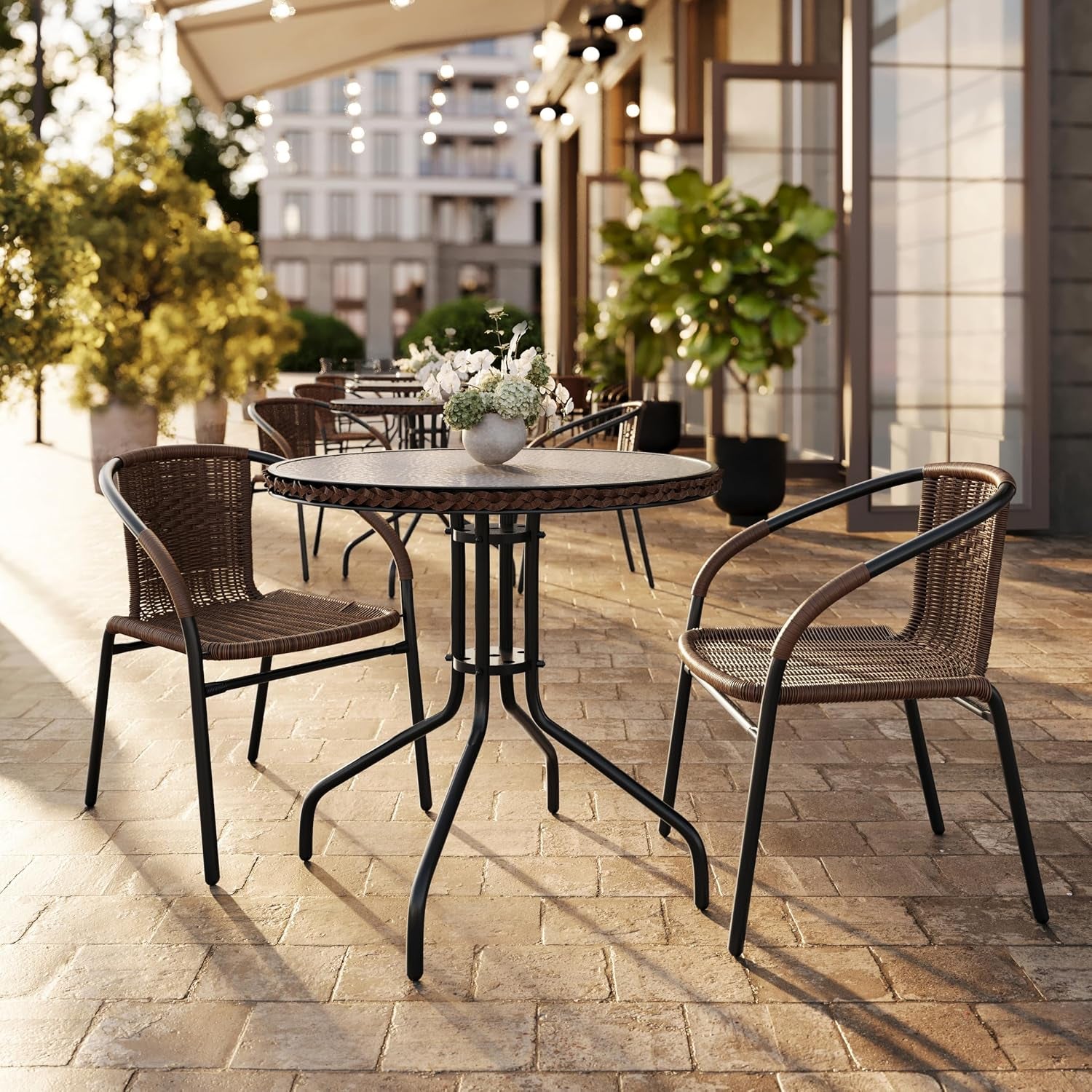 Multiple brown woven chairs arranged around round bistro tables on a sunlit outdoor café patio