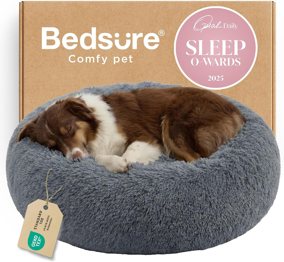 Front view of a gray faux-fur donut dog bed with a brown dog curled asleep, a tag visible at the front and a cardboard box