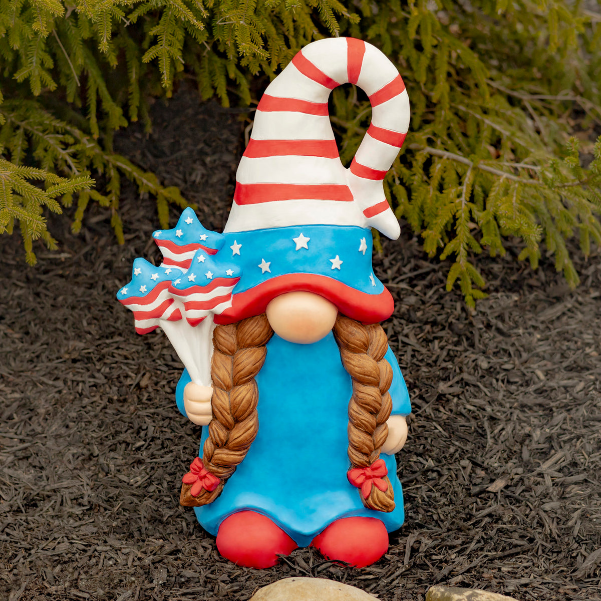 Front view of a colorful braided garden gnome standing in a garden bed