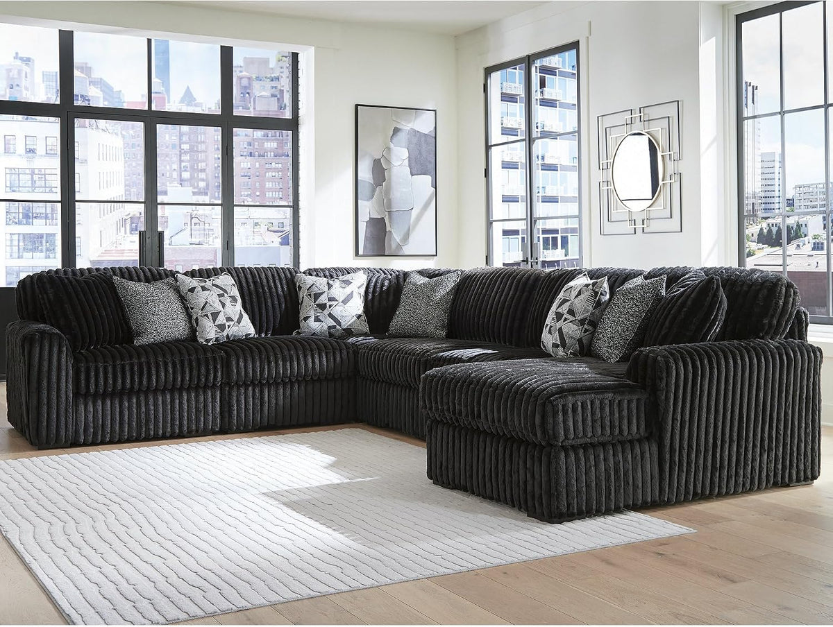 Large sectional arranged in a bright living room with floor-to-ceiling windows and a light area rug.