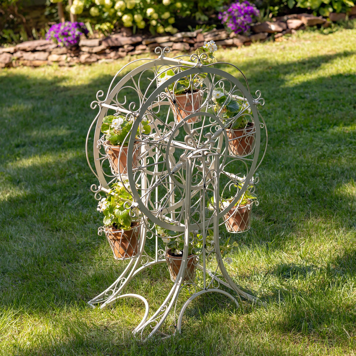 Antique white ferris wheel stand with flower baskets in a sunny garden