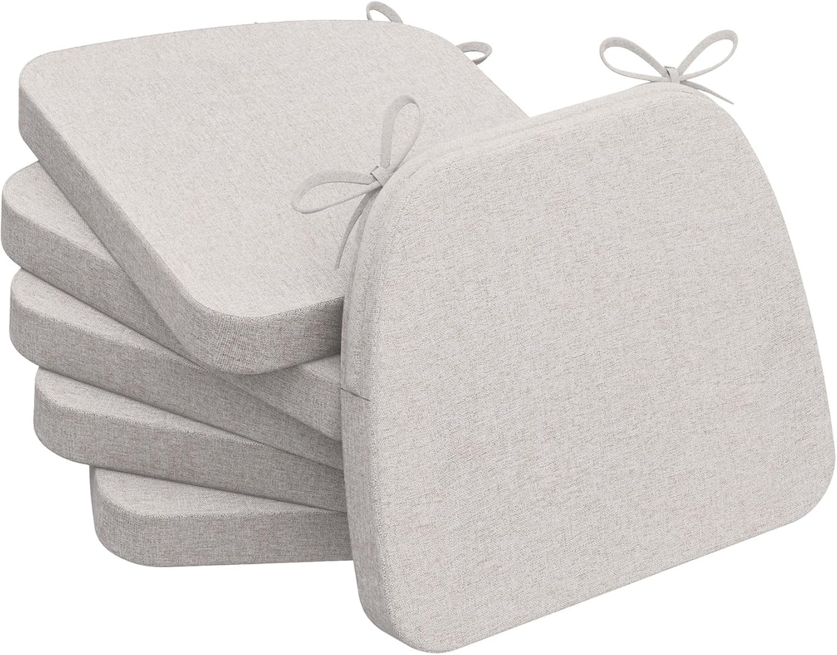 Stack of four light oatmeal-beige D-shaped chair cushions with ties visible at top