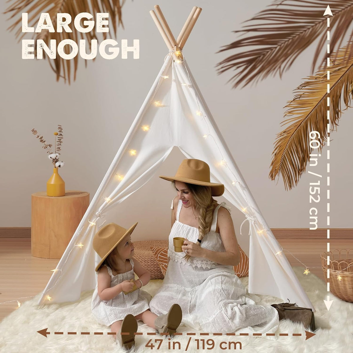 Woman and child sitting inside a white teepee lit with star lights, shown on a fluffy rug