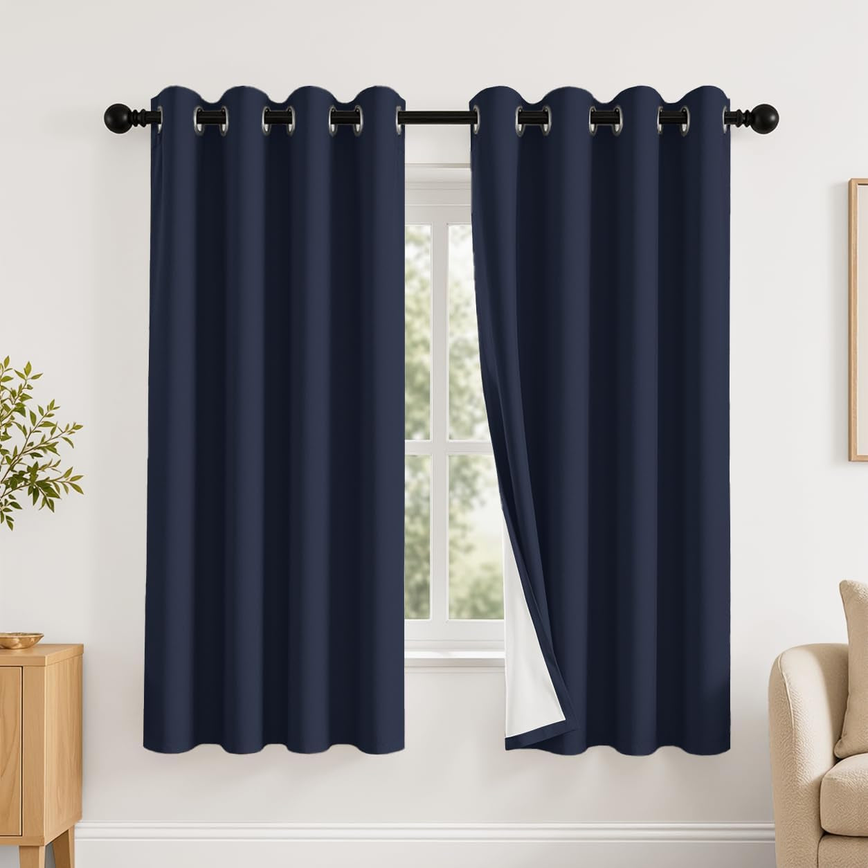 Navy curtains hung on a rod with one panel pulled aside showing the white reverse lining.