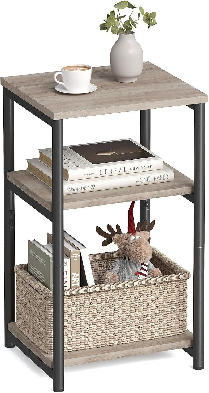 Three-tier square side table with light gray wood shelves and black legs, styled with cup, vase, books and a toy in a basket.