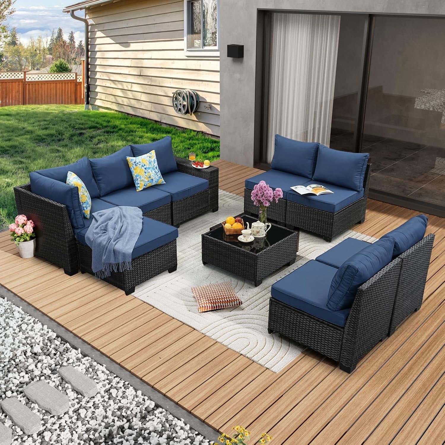 Overhead view of patio set with navy cushions, separate loveseat pieces and a square glass coffee table on a rug.