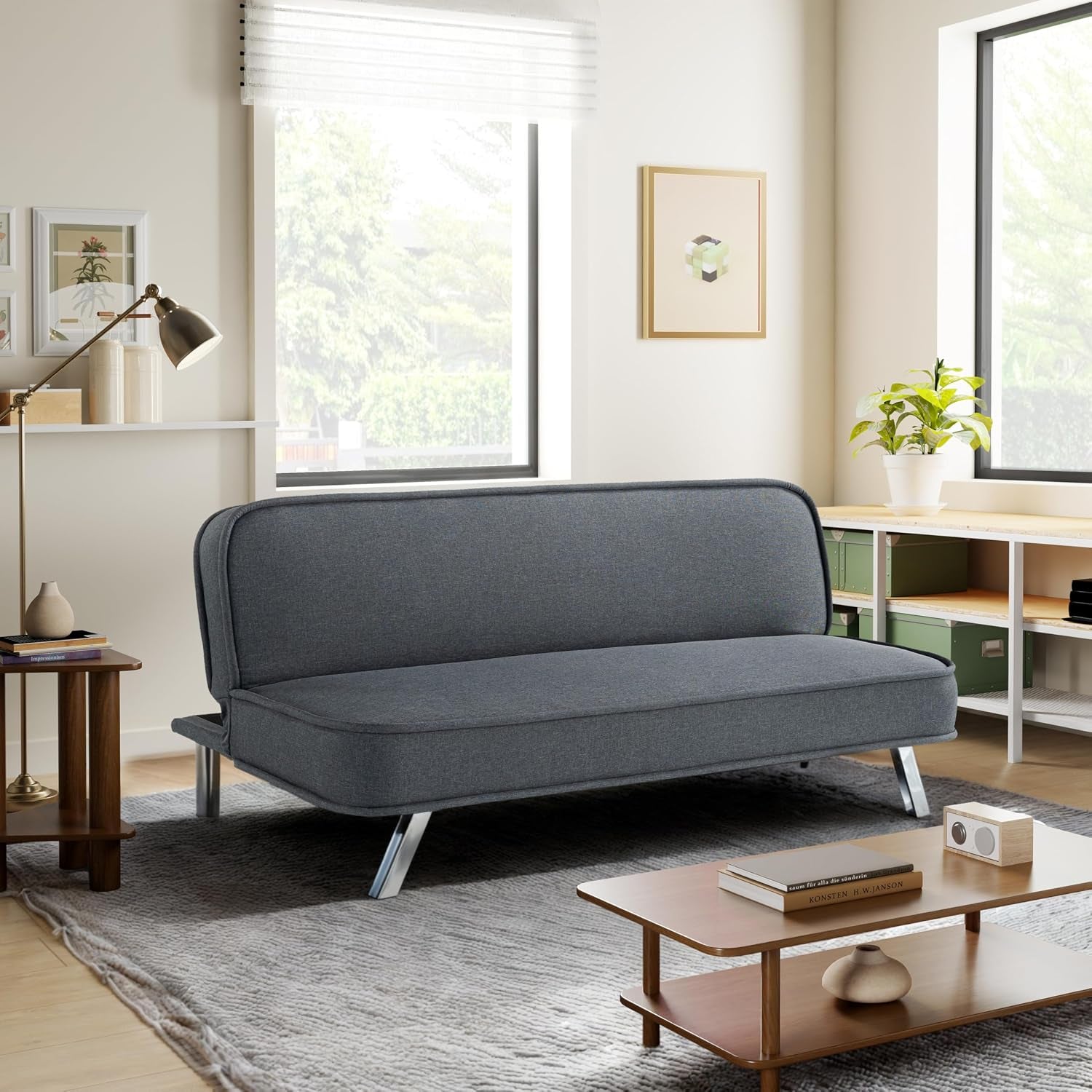 Dark navy convertible futon sofa in a bright living room with metal legs and a gray rug.