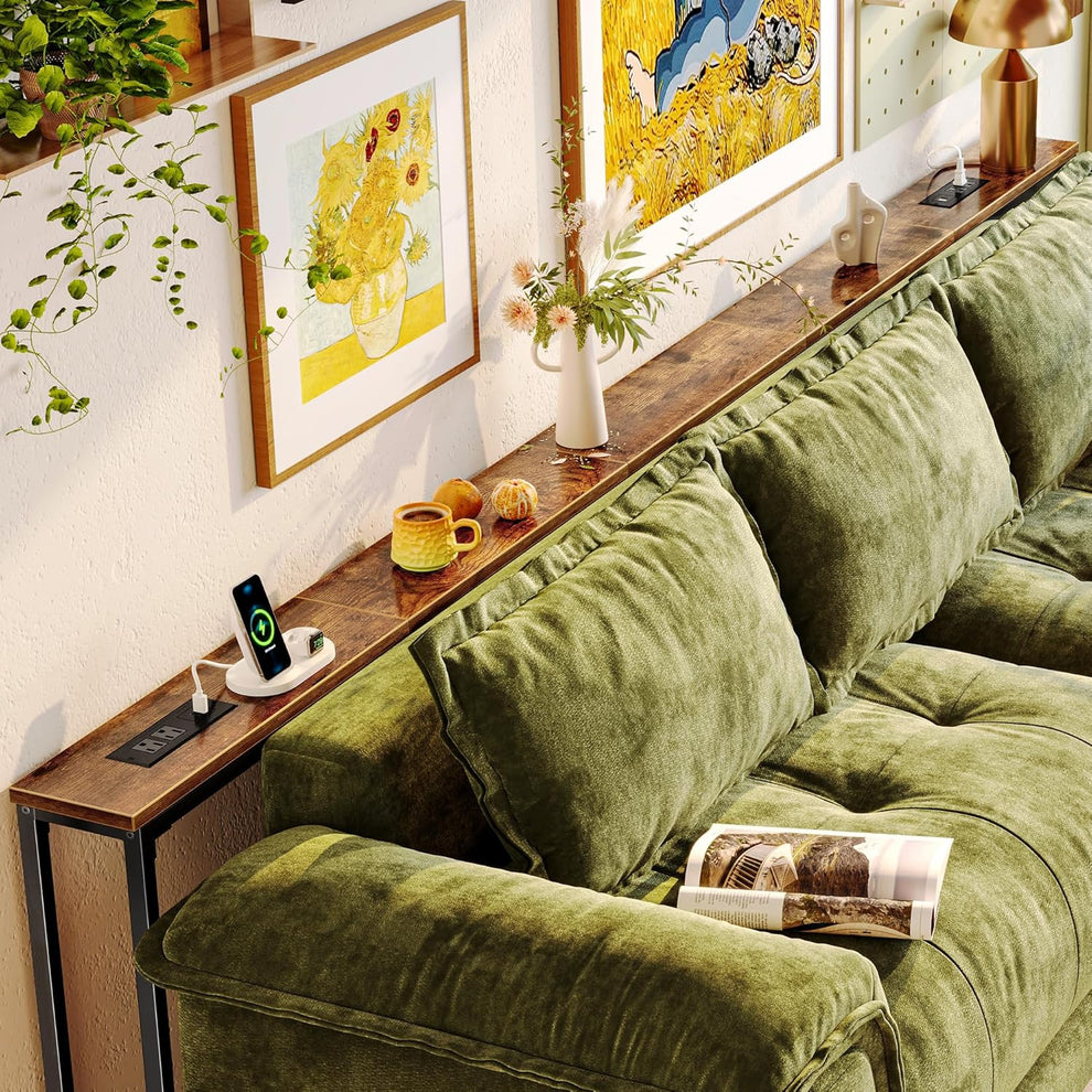Long narrow console table placed behind a green sectional sofa, showing a rustic wood top and a black power module.