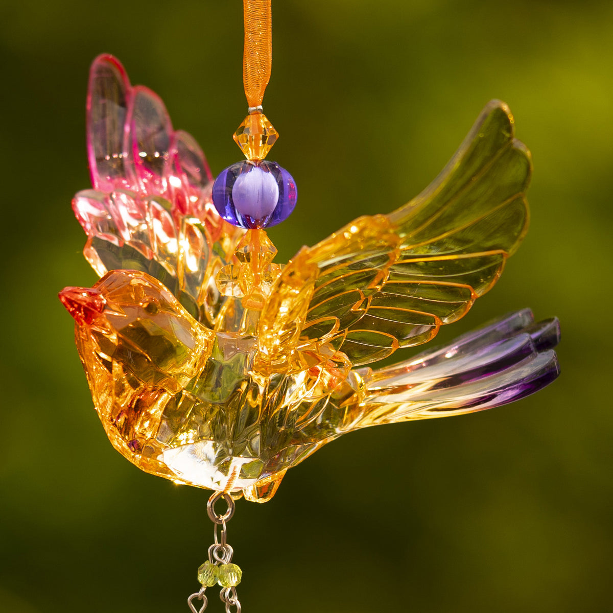 Close-up of a translucent bird ornament with a purple bead, sculpted wing feathers, and dangling bead strands.